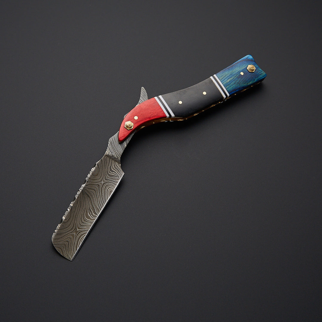 Damascus steel straight razor blade showing detailed wave pattern and ultra-sharp cutting edge for wet shaving.